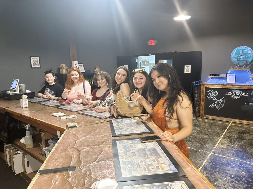 6 friends smiling at a distellery in nashville