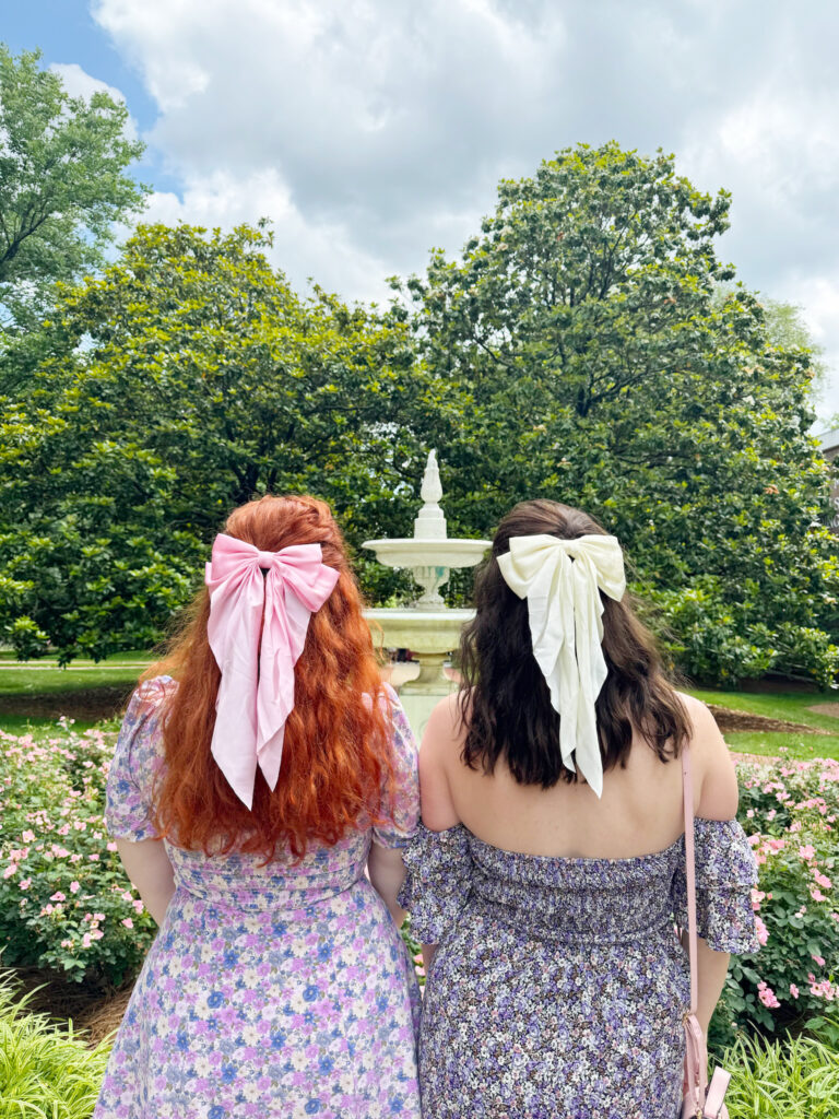 two girls from behind with bows in the hair in front of a pretty garden in nashville