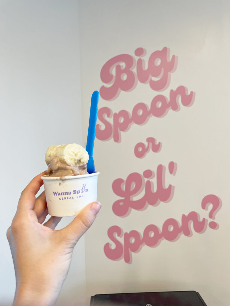 a small cup of icecream with bannans on it in front of a mural that says big spoon or little spoon in nashville